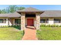 Inviting front entrance with a brick walkway and red double doors, framed by brick pillars and manicured landscaping at 117 Orange Ridge Dr, Longwood, FL 32779