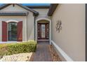 Inviting front entry with a brick walkway, decorative wall art, and meticulously maintained landscaping at 2530 Stargrass Cir, Clermont, FL 34715