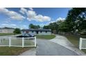 Wide view of light blue home with solar panels, black car in driveway, and white picket fence at 434 Diamond Acres Rd, Davenport, FL 33837