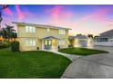 Bright yellow two-story home featuring a spacious lawn at sunset at 5224 Saint Regis Pl, Belle Isle, FL 32812