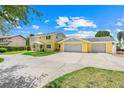 Bright yellow two-story home with a spacious three-car garage and large driveway at 5224 Saint Regis Pl, Belle Isle, FL 32812