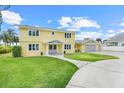 Bright yellow two-story home featuring a spacious lawn and attached two-car garage at 5224 Saint Regis Pl, Belle Isle, FL 32812