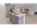 Modern kitchen featuring an island with a sink, stainless steel appliances, and gray cabinets at 543 Pine Tree Bridge Trl, St Cloud, FL 34772