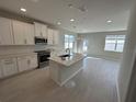 Open concept kitchen, featuring white cabinets, stainless steel appliances, kitchen island, and tile floors at 620 Pothos St, Apopka, FL 32703