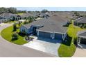 Aerial view of a beautiful single-story home, boasting a three-car garage and decorative concrete driveway at 6328 Merhottein Loop, The Villages, FL 32163