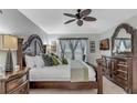Spacious primary bedroom features tile flooring, large window, and an elegant, oversized, decorative wood bed frame at 8471 Secret Key Cv, Kissimmee, FL 34747