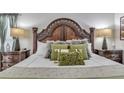 Luxurious primary bedroom with an ornate headboard, decorative pillows, and stylish nightstands with lamps at 8471 Secret Key Cv, Kissimmee, FL 34747