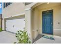 Close up of the blue front door and two-car garage with a concrete driveway at 1068 Brooklet Dr, Davenport, FL 33837