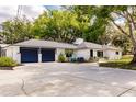 Spacious driveway leading to a white home with a dark garage and seating on the front porch at 120 W Trade Winds Rd, Winter Springs, FL 32708