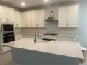 Modern kitchen featuring white cabinets, a spacious island, stainless steel appliances, and a stylish range hood at 16759 Muskgrass Dr, Winter Garden, FL 34787