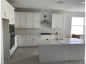 Bright kitchen featuring a large island, stainless steel appliances, white cabinets, and modern backsplash at 16759 Muskgrass Dr, Winter Garden, FL 34787