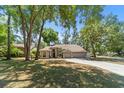 Well-maintained house showing its front lawn, arched window, and a three-car garage bordered with mature trees at 2082 Nexus Ct, Apopka, FL 32712