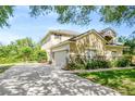 Exterior shot shows long driveway leading to the home's two-car garage, highlighted by stonework and manicured lawn at 2401 Home Again Rd, Apopka, FL 32712