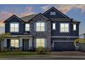 Charming two-story home featuring a stone facade, gray paint, and a two-car garage at dusk at 2628 Cedar Shake Ct, Oviedo, FL 32765