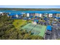 This image showcases the community tennis courts surrounded by lush greenery and blue roofed carports at 2700 N Peninsula Ave # 215, New Smyrna Beach, FL 32169