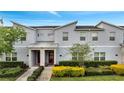 Charming townhome featuring a modern facade, red door, covered entry, and professionally landscaped front yard at 368 Ocean Course Ave, Davenport, FL 33896