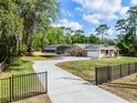 Single-story home with carport, long driveway, gated entrance, and well-maintained lawn with mature trees at 1201 Groveland Dr, Chuluota, FL 32766