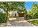 Beautiful two-story home features lush landscaping, paver driveway, wood garage door covered by greenery, and balcony at 1665 Temple Dr, Winter Park, FL 32789
