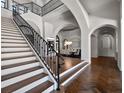 Bright foyer boasts a staircase with dark iron railings and herringbone-patterned wood floors at 16812 Vinci Way, Bella Collina, FL 34756