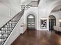 Elegant foyer featuring a grand staircase, dark wood floors, arched doorway, and stylish decor at 16812 Vinci Way, Bella Collina, FL 34756
