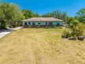 Inviting single-story home boasts a lush green lawn, mature trees, and a welcoming facade under the bright sun at 3975 Rambler Ave, St Cloud, FL 34772