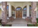 Elegant front entrance with double doors, arched windows, brick columns, and two inviting benches at 58 Golf View Dr, Ocala, FL 34472