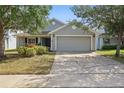 Inviting single-story home showcasing a gray exterior, manicured front yard, and a convenient two-car garage at 634 Chadbury Way, Kissimmee, FL 34744