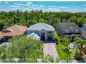 Beautiful home featuring a gray roof, lush landscaping, a brick driveway, and mature trees surrounding the property at 9076 Lake Avon Dr, Orlando, FL 32829