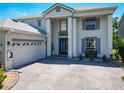 Striking home featuring a three car garage, gray shutters, brick driveway, and well maintained landscaping at 9076 Lake Avon Dr, Orlando, FL 32829