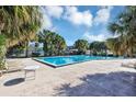 Large community pool surrounded by palm trees and lounge chairs on a sunny day at 1728 Townhall Ln # 1728, Orlando, FL 32807