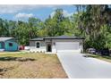 Inviting single-story home with a two-car garage and a long driveway, surrounded by lush trees at 1819 Carr St, Deland, FL 32720