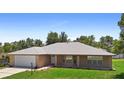 Well-maintained brick home with a lush green lawn and freshly painted garage door at 1889 Eden Dr, Deltona, FL 32725