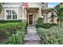 Charming home entrance with a flag, brown door, well-kept shrubbery, and a brick paver walkway at 8111 Pacific Loon St, Winter Garden, FL 34787