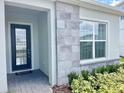 Home entryway with a black-framed door, stone accents, a welcome mat, and lush landscaping at 10275 Park Estates Ave, Orlando, FL 32836