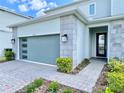 Two-story home with a modern garage door, stone accents, manicured landscaping, and a paver driveway at 10275 Park Estates Ave, Orlando, FL 32836