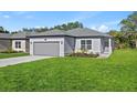 Charming single-story home featuring a two-car garage, grey exterior paint, and a well-manicured front lawn at 108 Alta Vista Way, Davenport, FL 33837
