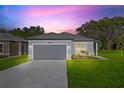 Charming single-story home featuring a two-car garage, grey exterior paint, and a well-manicured front lawn at 108 Alta Vista Way, Davenport, FL 33837