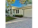 Beige home featuring an attached garage and beautiful brick paver driveway at 145 Burns Ave, Longwood, FL 32750