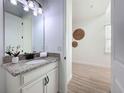 Well-lit bathroom featuring a granite countertop, white cabinets, and a decorative mirror enhancing the space at 15727 Vetta Dr, Montverde, FL 34756