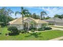 Single-story home with lush landscaping, palm trees, and a tile roof under a sunny sky at 216 Hammock Oak Cir, Debary, FL 32713