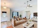 Cozy living room with a plush sofa, modern decor, ceiling fan, and ample natural light at 2984 Monica Ter, Kissimmee, FL 34744