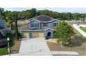 Aerial view of a two-story home with blue exterior, brown shutters, three-car garage, and solar panels at 4058 Brookshire Cir, Eustis, FL 32736