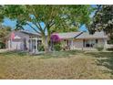 A lovely single-story home boasts manicured lawn, mature trees, and pergola covered walkway to the front door at 623 Green Meadow Ave, Maitland, FL 32751