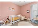 Cozy Bedroom with soft pink walls, white crib, and comfortable rocking chair at 10006 Quail Meadow Aly, Winter Garden, FL 34787
