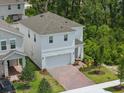 Bright two-story home featuring a brick driveway, two-car garage, landscaping, and a well-maintained lawn at 1096 Happy Forest Loop, Deland, FL 32720