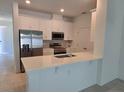 Bright kitchen boasts white cabinetry, stainless steel appliances, quartz countertop and an island sink and faucet at 1096 Happy Forest Loop, Deland, FL 32720