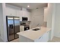 Modern kitchen featuring white cabinets, stainless steel appliances, and a sleek countertop with an island sink at 1096 Happy Forest Loop, Deland, FL 32720
