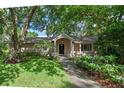 Charming home with mature trees, blooming flowers, and a covered entryway at 1105 Lake Nettie Dr, Eustis, FL 32726