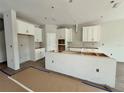 Spacious kitchen area featuring white cabinets, an island, and wood-look tile flooring at 1157 Basalt Ln, Sanford, FL 32771
