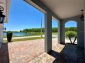 Covered front porch with brick flooring provides a view of a serene lake surrounded by lush trees at 2648 Needlepoint St, Kissimmee, FL 34741